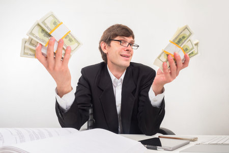 Satisfied man shows profit. Businessman with money on a light background. Businessman demonstrates...