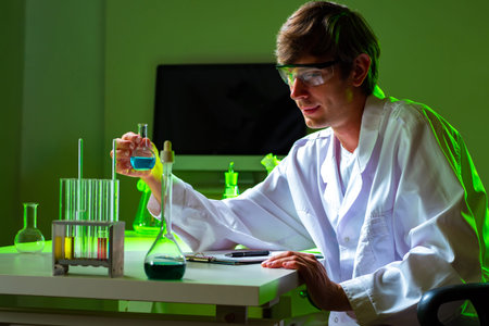 Man is conducting laboratory tests. Lab assistant picks up a small test tube in his hands. Medic is...