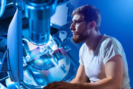Research in field of electronics. Concept - engineer develops microprocessors. Man in the production of microchips. Man works a computer. Development machines for creating electronic circuit boardsの写真素材