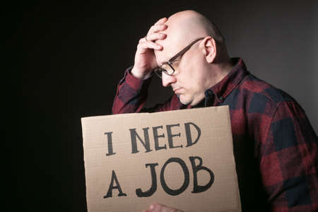 Unemployed in search of work. Man shows the sign I need a job. Concept - human was fired due to the crisis. Adult Male Looking I need a job. Human upset by dismissal. Workers protests. Dismissal.の写真素材