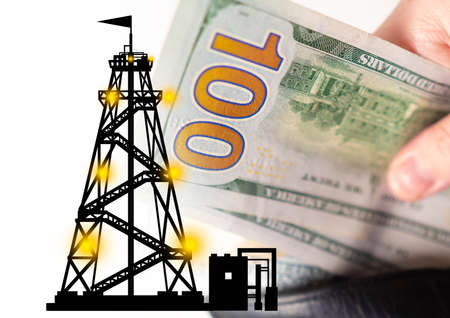 Oil prices. Concept - buying oil companies. Concept - investments in the petroleum industry. Oil trade. Dollars in the hands. Money next to the silhouette of an petroleum rig. Hydrocarbon cost.の写真素材