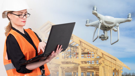 Woman in builder uniform. Concept - girl controls a drone from a laptop. Inspection of the building...