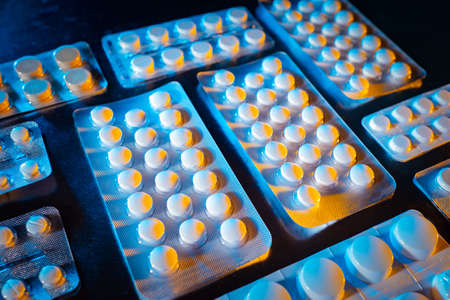 Pharmacy medicines. Medical devices are on the table. White pills in pack. Plates with medicines as a symbol of pharmaceuticals. Concept - pharmaceutical production. Concept - antibiotic treatmentの写真素材