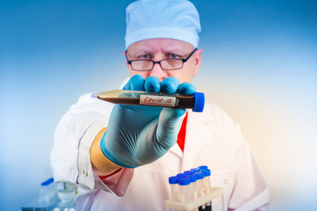 Cornavirus. A doctor shows a test tube with Covid 19. Blood in the test tubes is infected with the...
