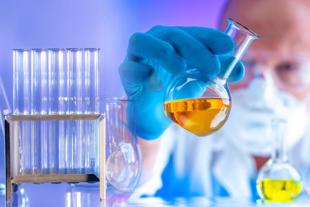Chemistry laboratory. Male laboratory assistant with a test tube in his hands. Man works in a...