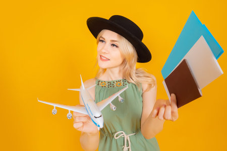 Traveler woman with a model airplane in her hands. Girl with hat on an orange background. Traveler...