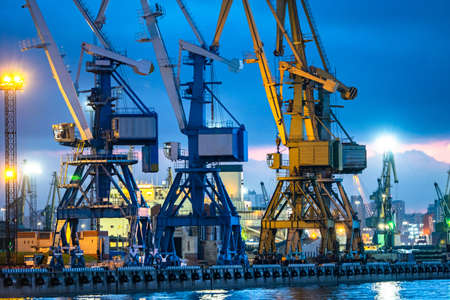 Sea ports view from sea. Several loading cranes at seaport. Installations for loading in seaport. Tower cranes at the cargo port. Marine loading terminal on background of the evening sky.の写真素材