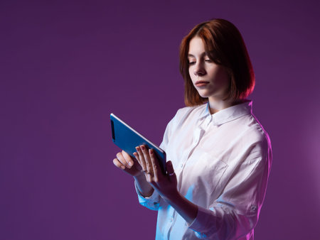 A girl with a tablet computer in her hands. A woman in a white shirt is holding an electronic...