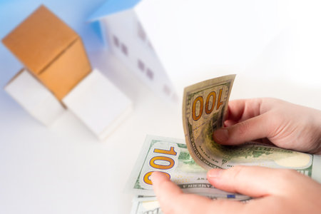 Sending parcels. Concept - delivery of packages to door. Money in the hands of man. Boxes near the entrance to the house. Concept - contactless transfer of the order. Delivery from the online storeの写真素材