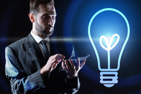 Glowing light bulb next to a businessman. Businessman in a business suit. A man with a tablet on a...