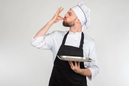 Chef man. Portrait of chef cook showing empty tray. Cook shows something very tasty. Chef makes...