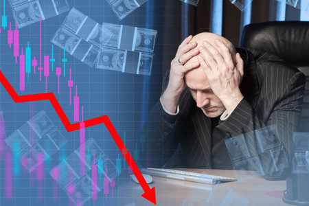 Owner of stock is upset by drop in quotes. Man in office is somewhat upset. Investor is holding on to his head. Falling chart symbolizes a fall in stocks. Lower company stock value. Investor upsetの写真素材