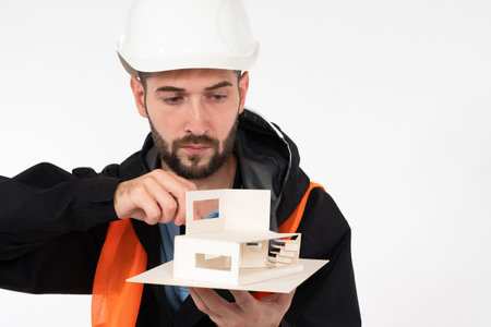 Male architect with a layout of the house in his hands. Construction engineer in a hard hat. An...