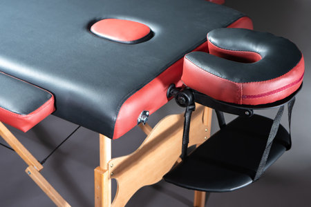 Part of the massage table close-up. Ergonomic massage table. Workplace of the masseur. Medical massage bed without people. Equipment of a medical clinic.の写真素材