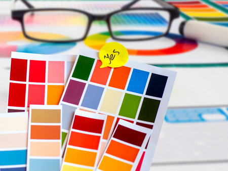 Glasses are on the color palette. Concept - choice of colors for design. Yellow sticker on red. Concept - designer chose red color. Coloring samples are shown on paper. Coloring palette close-up.の写真素材