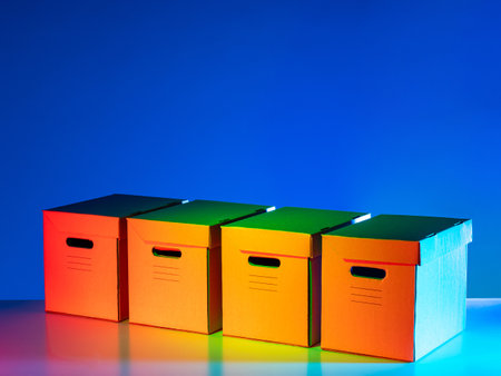 Four cardboard boxes on a blue background. Cardboard storage boxes with carry holes. Concept - Archival corrugated boxes. Packaging for archival documents. Sale of packaging stationeryの写真素材