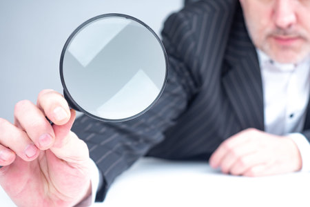 Magnifying glass in hands of a businessman. Human is considering something. Man holds out a...