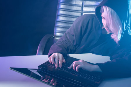 Girl programmer next to a laptop. Programmer in a chair on a dark background. Computer programmer...