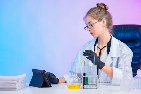 Pharmaccept is developing a medicine. Young lab technician with test tubes in her hands. Concept - student is studying virology. Virologist looks at the tablet. Workplace Epidemiologist. Vaccine.の写真素材