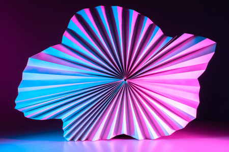 Macro image of paper folded in the form of a fan. Abstract geometric background in neon lighting. Partially blurred three-dimensional image of a paper object.の写真素材