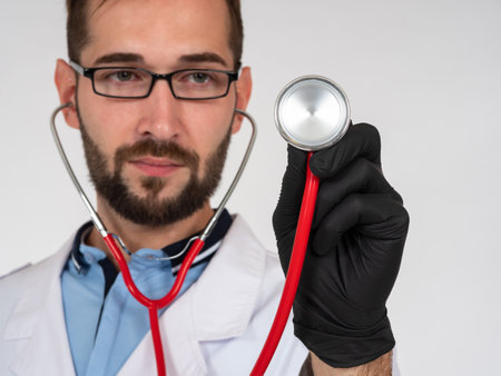 Doctor puts a stethoscope to screen. Concept - medical services. Medic with device for listening to heart. Doctor treats heart disease. He works in medical center. Medical examination.の写真素材