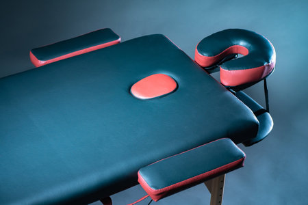 Massage table close-up. Massage table with headrest and hand rests. Ergonomic daybed for medical procedures. Equipment of the massage room.の写真素材