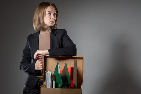 Woman who lost her job on a gray background with place for text. Woman stands and leans on office...