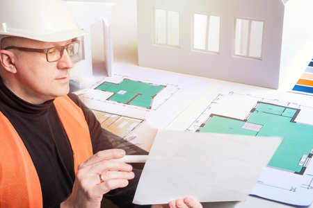 Builder is looking at plans of the architect. Builder next to drawings of the premises. Concept - architect develops an internal layout. Development of construction drawings. Man works architect.の写真素材