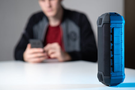 Wireless speaker stands on a table against the background of a silhouette of a person with a...