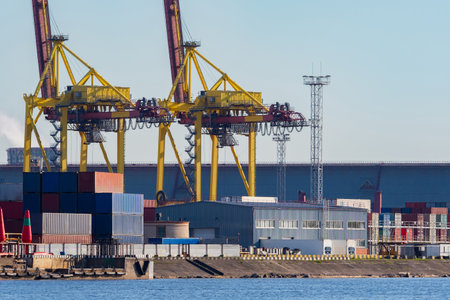 Commercial port. View of the warehouse in the port and gantry cranes. Cranes and containers with cargo in the port. Transportation of goods by water transport. Loading and unloading operations.の写真素材