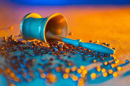 Preparation of the coffee. Coffee beans and a mortar are on the table. The metal mortar, pestle, and coffee beans are brightly lit. Bright still life with coffee and mortar.の写真素材