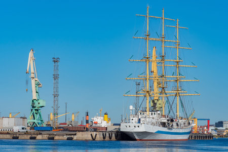 The yacht is moored at the pier in the port. Sailboat close-up. A ship with sails on the background...