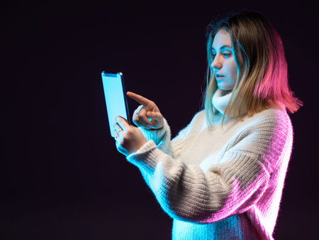 Girl with an electronic tablet. Woman holding tablet computer isolated on dark background. Working...
