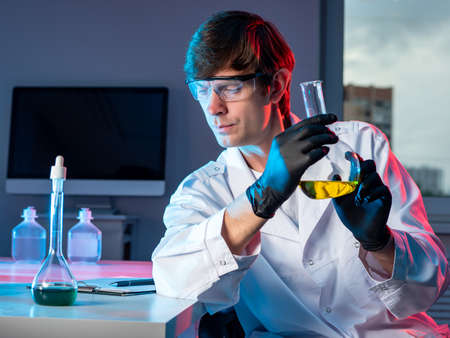 Male chemist with a flask in his hand. Scientific research in the chemical laboratory. Discoveries in the field of chemistry. Chemist working in a laboratory and doing research. Passion for chemistry.の写真素材