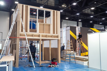 Preparation for the exhibition. Installation of structures in the exhibition hall. Workers install advertising structures before the opening of the exhibition. Construction work.のeditorial素材