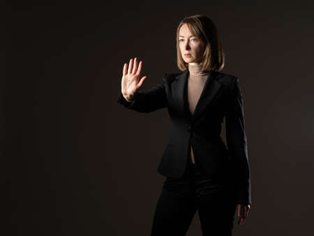 The woman makes a stop sign with her hand. She makes a stop sign with her hand. She calls to stop. The woman makes a protective gesture. The girl forbids anyone to approach her. Defensive gestures.の写真素材