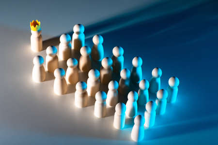 The concept of leadership. The leader leads the way. Service subordination. The man in the crown leads the way. Identical little men without faces. Team management.の写真素材