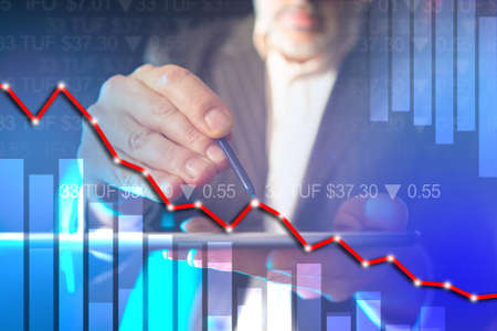 Trading on the stock exchange. Falling chart and stock quotes. The man points to a point on the chart. Break-even point. Business on investment. Speculative operations on the stock exchange.の写真素材