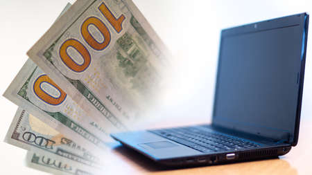 Laptop and money on a white background. Concept - remote work on the Internet. Laptop with money as a symbol of freelance. Concept - money earned in the online business. Works using a computer.の写真素材