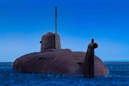 A submarine surfaced above the water. Part of the submarine peeps out of the sea. Concept - military naval forces. Naval military equipment. Submarine on the background of blue sky. Shipbuildingの写真素材