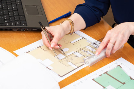 A person measures the size of the room according to the drawings. Architect with a ruler in his...