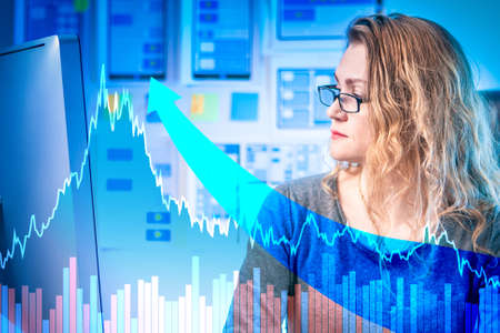 Woman is watching charts in the office. Company director checks the performance. Woman analyzes the causes of growth. Increase in inflation Growth of financial indicators of enterprise. Looks monitorの写真素材