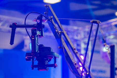 Professional video shooting. Concept - organization of video recording of an event. Crane for camcorder. Metal faucet with a fixed camera. Professional camera on the background of the concert venueの写真素材