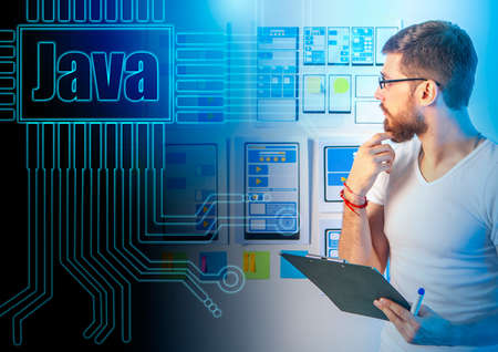 Java development language. Website development career. Concept - Front-end JavaScript developer. A man is considering mock-ups on the wall. Layouts of sites on paper. Work in an IT company. Java logoの写真素材