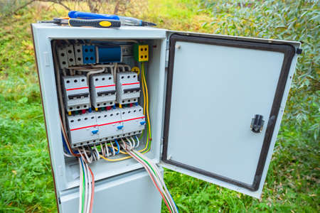 Electric panel on the street. Metal cabinet with electrical switches. Electric cabinet on background grass. Electrification cabinet. Concept for electrification of suburban housing. Electrical setupの写真素材