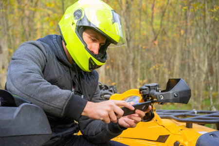 ATV driver holds a smartphone in his hands. Portrait of a motorcyclist with a phone. Concept - ATV...