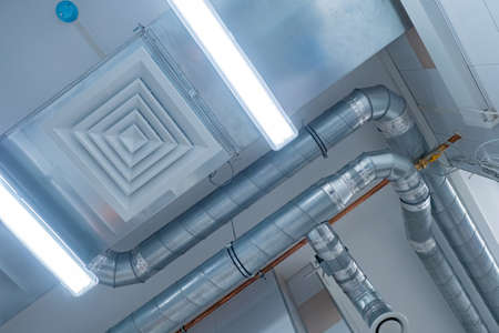 View of the ventilation pipes under ceiling. Ventilation pipes bottom view. Chrome plated pipes from an industrial hood. Concept is an industrial ventilation system. Air purification systemの写真素材