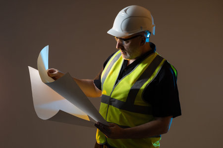 The engineer examines the drawings. A man in a work uniform with rolls of paper in his hands....