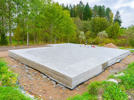 Concrete foundation next to trees. Construction near forest. Construction site with foundation. Foundation as a symbol of construction of a cottage. Building of a country cottage.の写真素材
