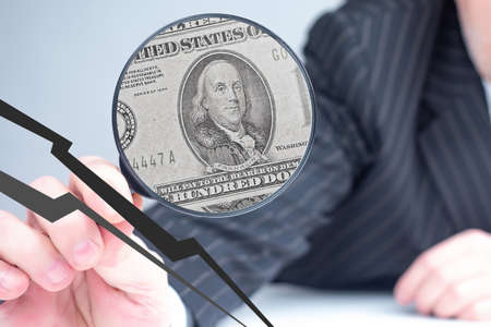 Bankruptcy lawyer concept. Charming glass with a reflecting dollar in a man hand. Bankruptcy lawyer service concept. Ð¡rack symbolizes financial problems leading to bankruptcy. Economic troublesの写真素材